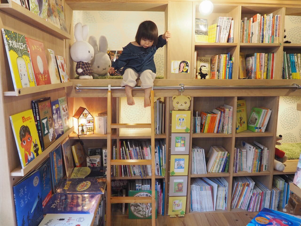 本棚のひみつ基地で絵本を楽しむ子ども